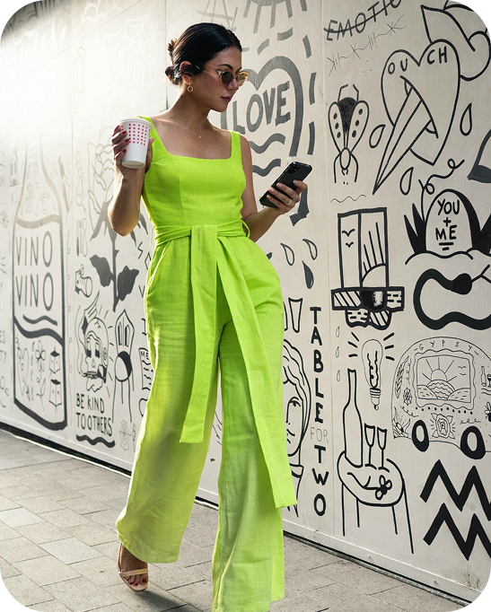 Girl dressed in lime having coffee and reading text on her phone